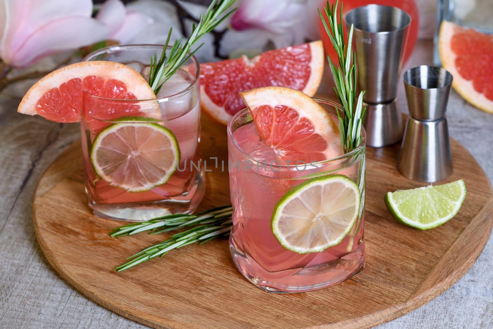 Refreshing organic cocktail with grapefruit slice, lime and rosemary sprig in a glass