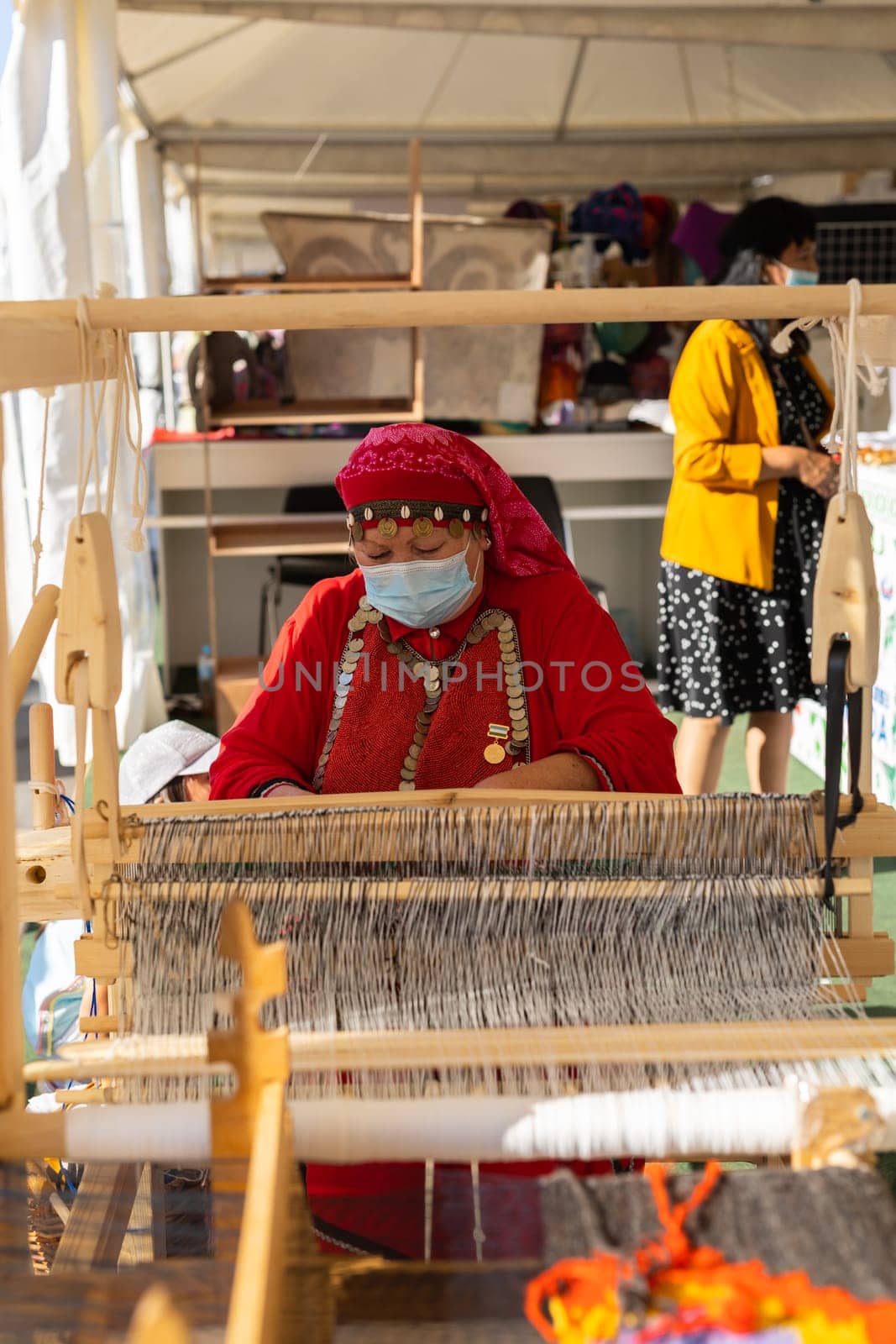 UFA, RUSSIA - JULY 10, 2021: Bashkir woman make carpet during Folkloriada in Ufa