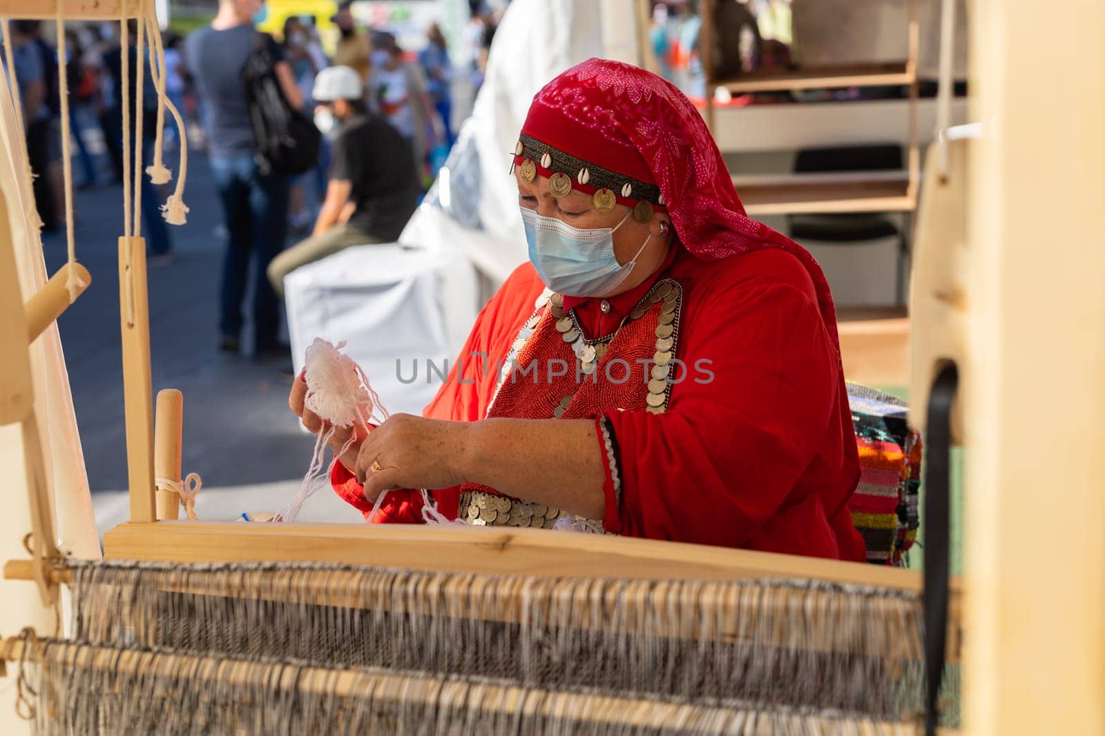 UFA, RUSSIA - JULY 10, 2021: Bashkir woman make carpet during Folkloriada in Ufa