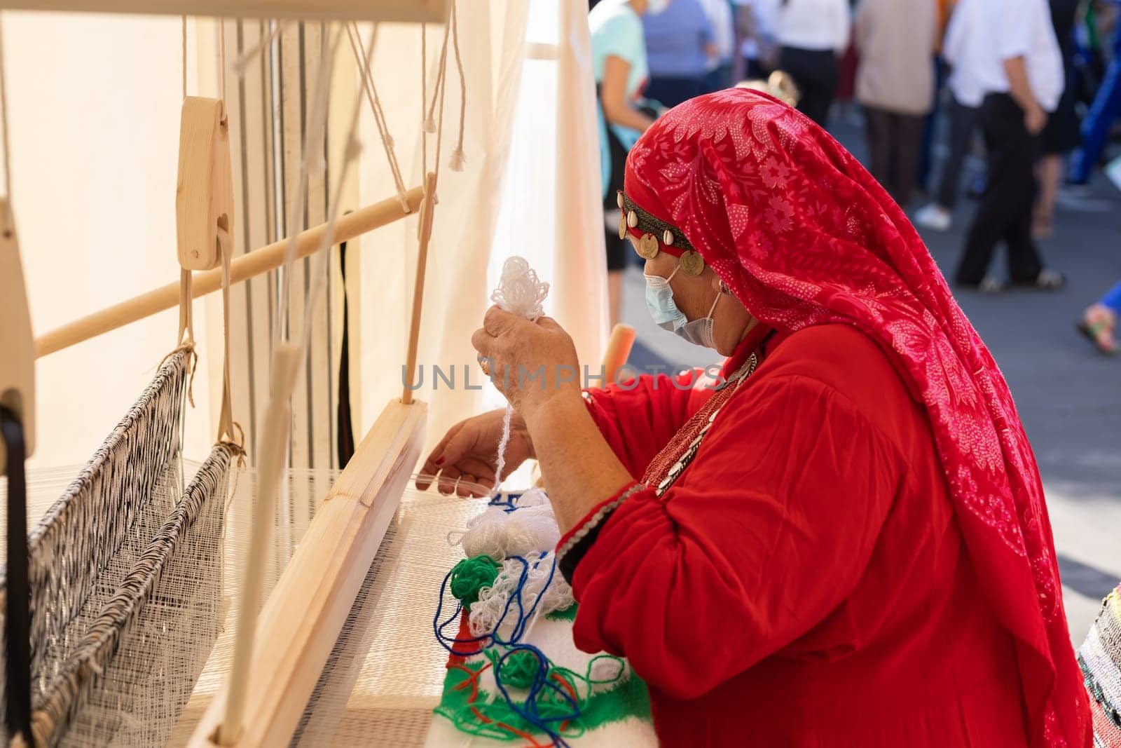 UFA, RUSSIA - JULY 10, 2021: Bashkir woman make carpet during Folkloriada in Ufa