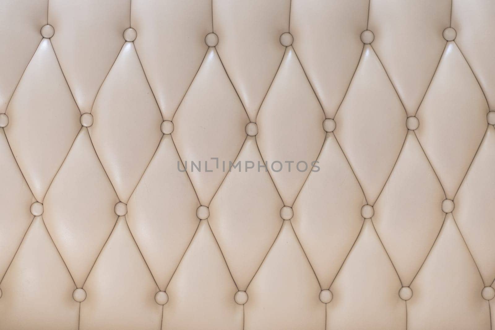 Elegant creamy beige leather upholstery texture with buttons for pattern or background.