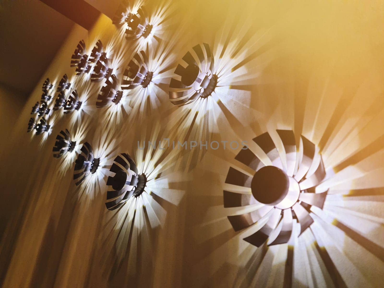A group of decorative modern light elements in the interior on the wall, giving a light-shadow pattern by Rom4ek