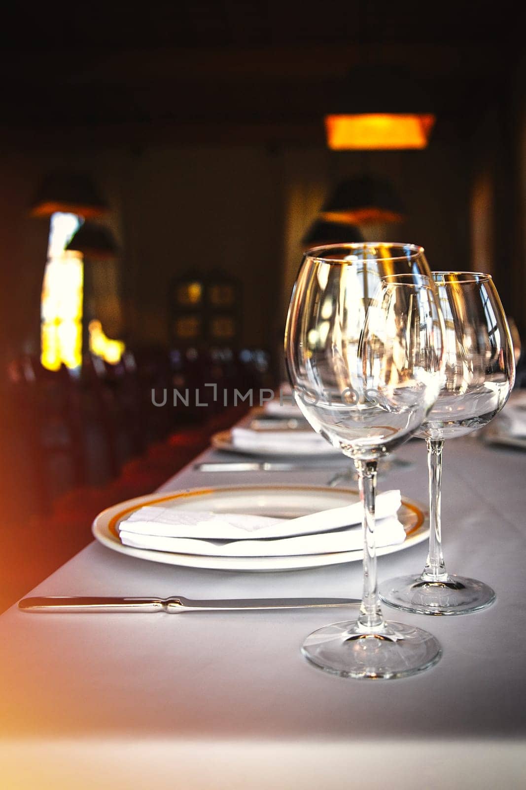Dining table set with wine glasses by the window in a luxury restaurant by Rom4ek