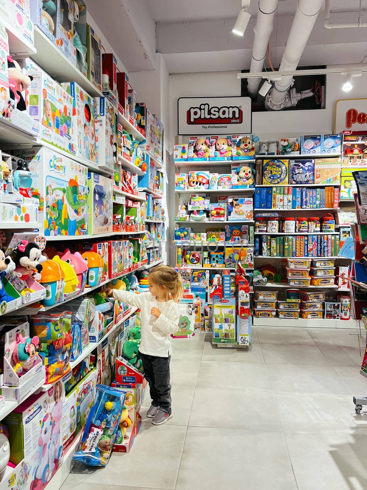 Budva, Montenegro - 01 november 2023: Little girl chooses a toy set on a store shelf by Nadtochiy