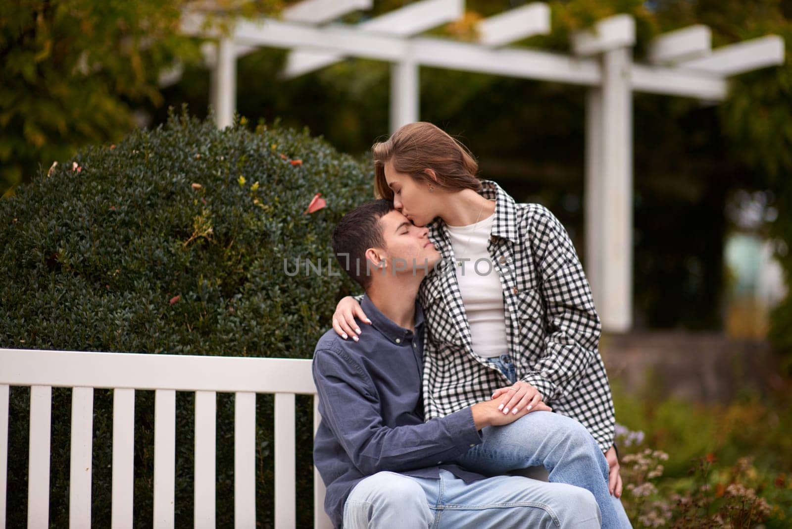 Autumn Romance: Young Couple Embracing and Kissing on Park Bench. Young couple kissing and rejoices at the lake. lovely young couple kissing outdoors in autumn. Embraced in Autumn's Warmth: Couple's Kiss on Park Bench. Loving couple walking in nature. Autumn mood. Happy man and woman hugging and kissing in autumn. Love. Fashionable couple outdoors. Fashion, people and lifestyle. Stylish couple in autumn outfit. by Andrii_Ko