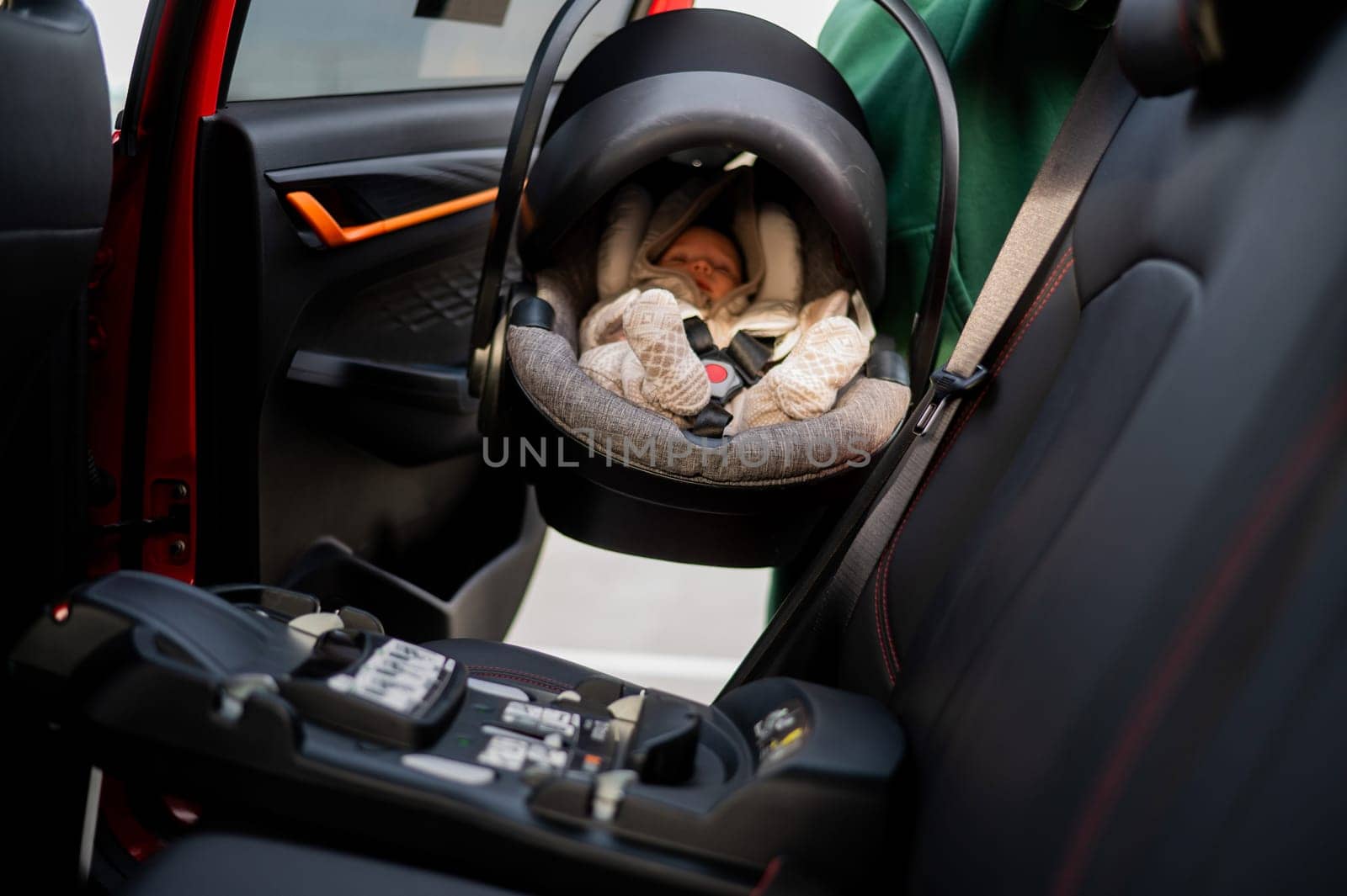 A Caucasian woman puts a child seat with a newborn baby in the car. Quick fastener. by mrwed54