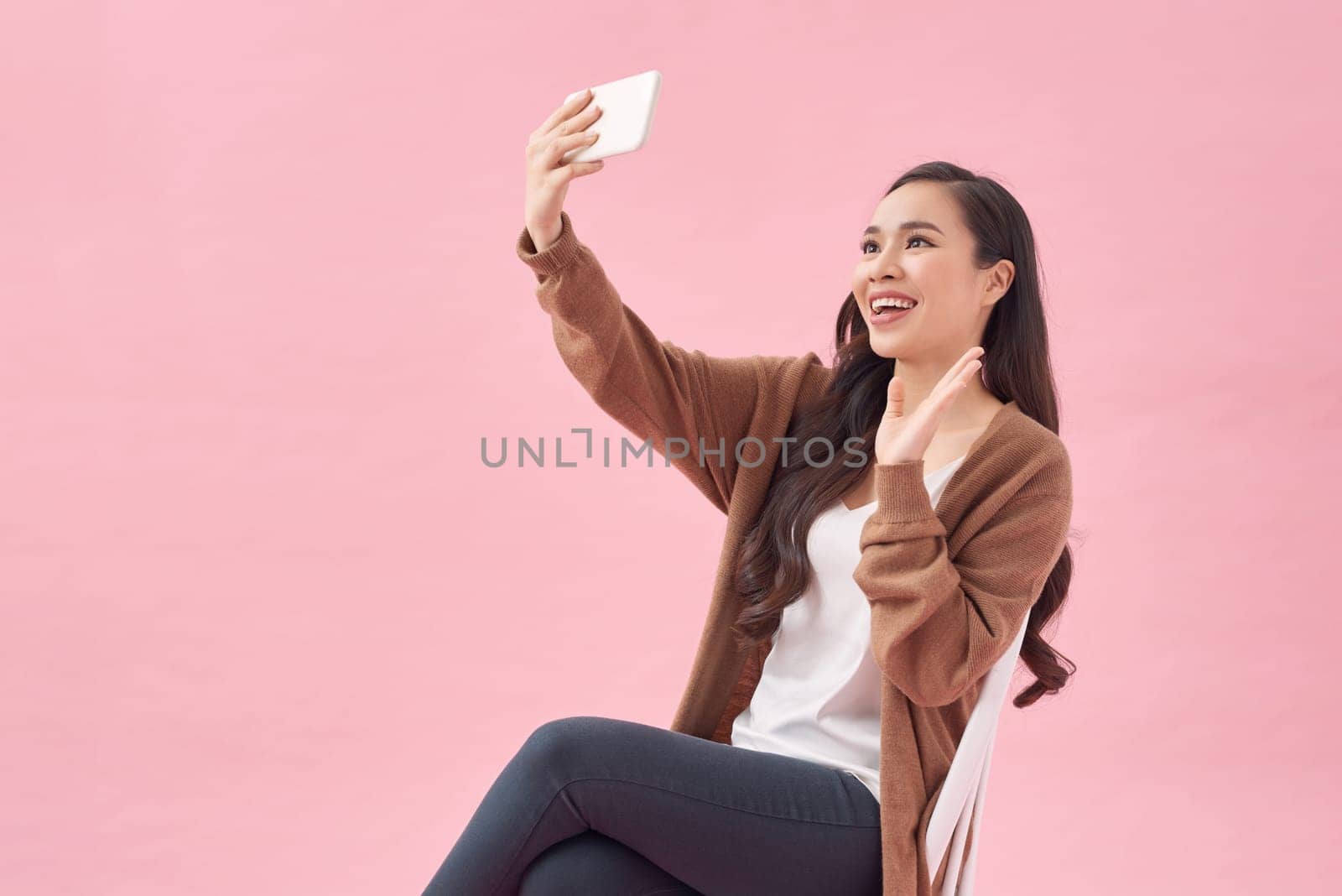 Fun cute smiling asian woman with long hair making self photo on mobile phone. by makidotvn