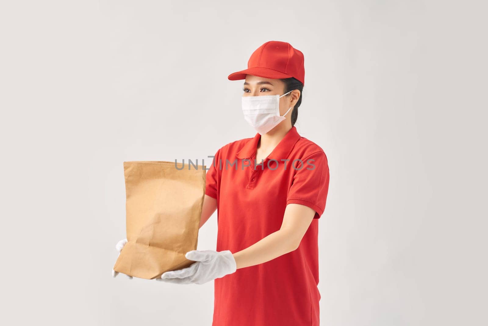 Young smiling asian delivery woman in red uniform holding paper bag food delivery