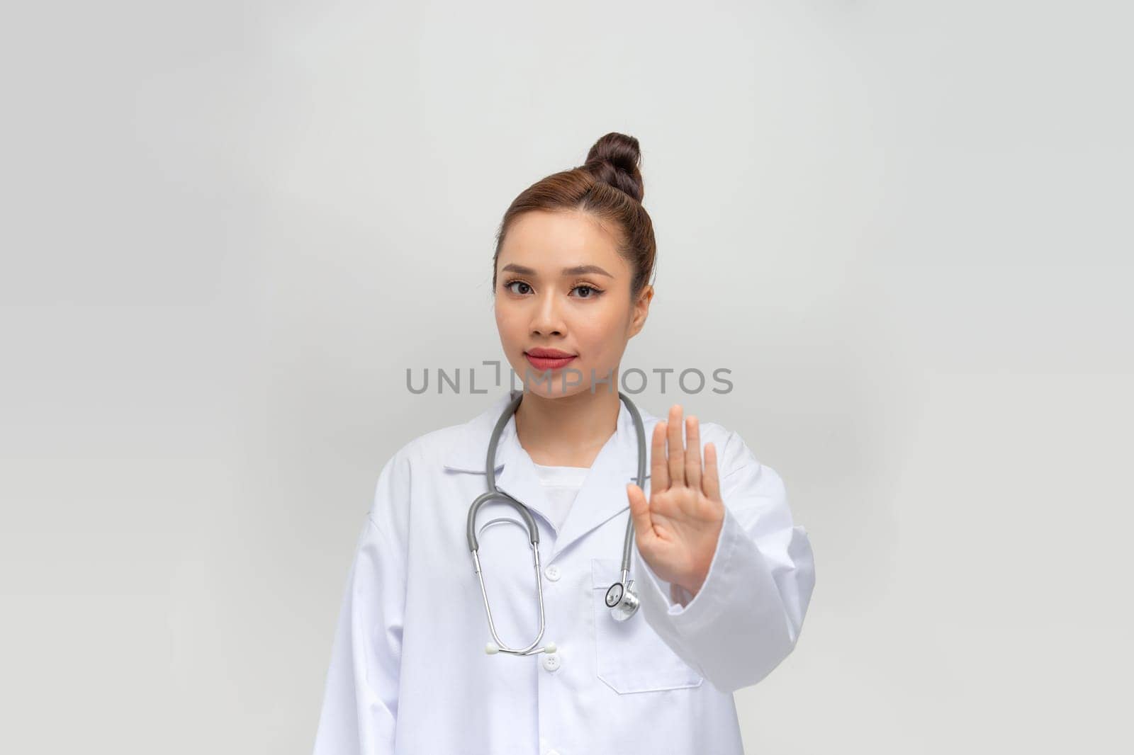 beauty female doctor in coat showing stop hand gesture