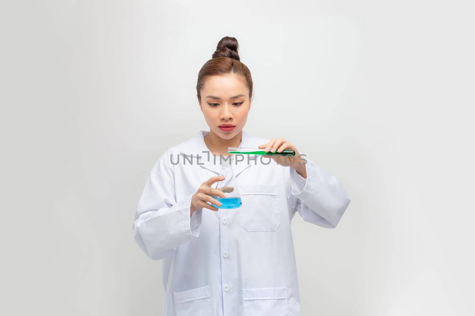 An Asia scientific researcher holding at a liquid solution in a lab.