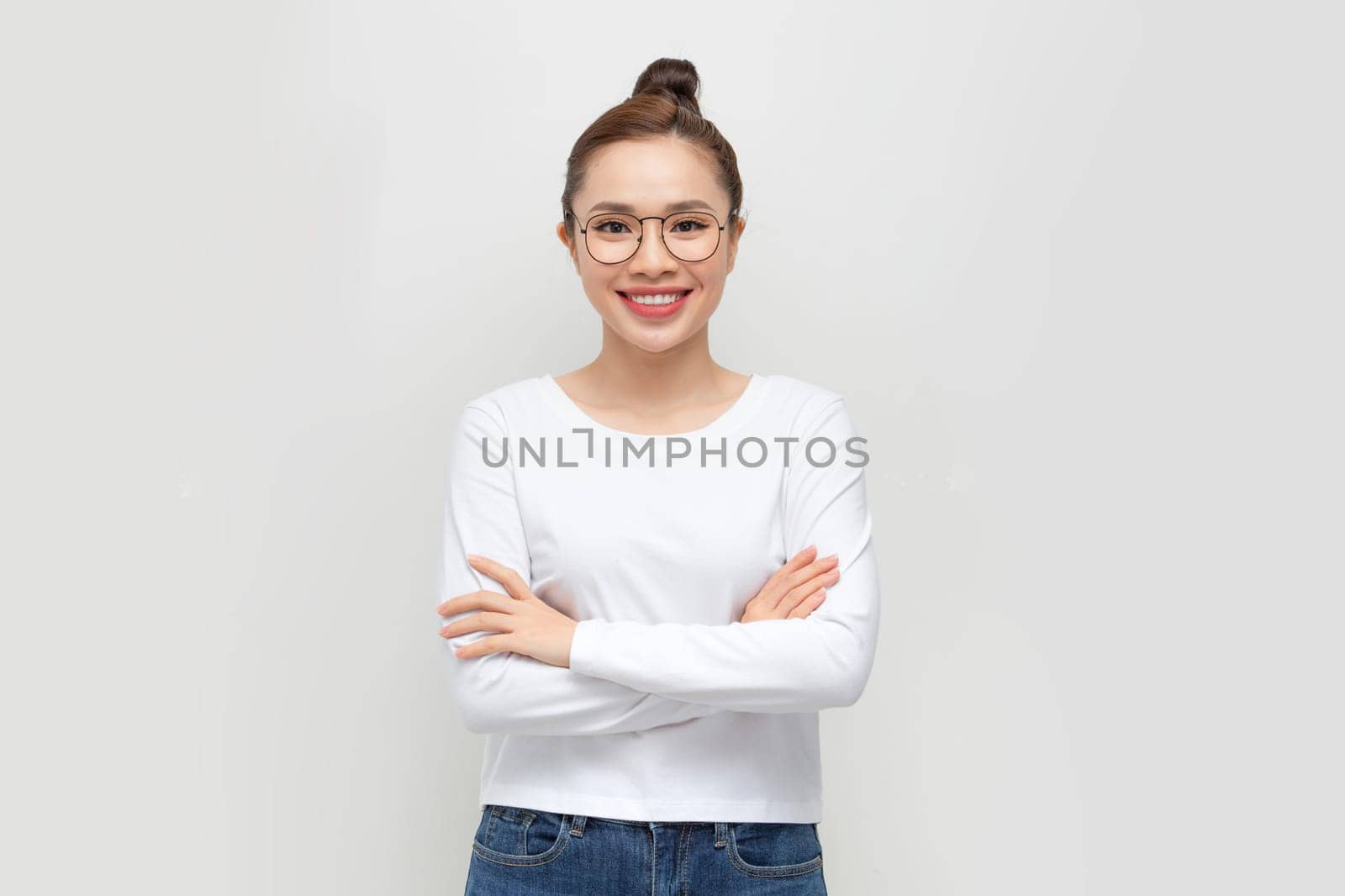 A cheerful woman student in white t-shirt, smiling confident and cheerful with arms folded