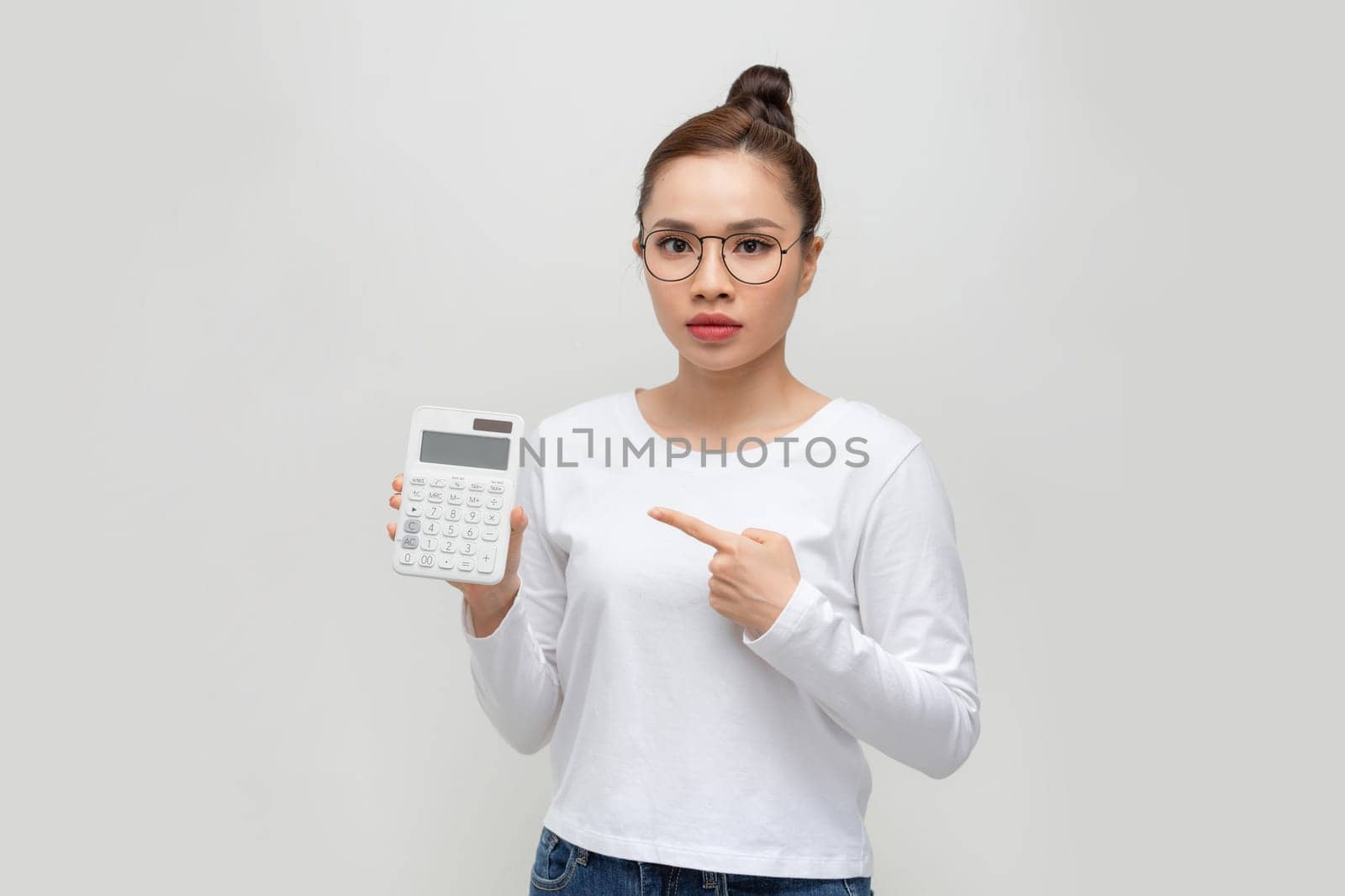 Pretty young businesswoman pointing at calculator on white background by makidotvn