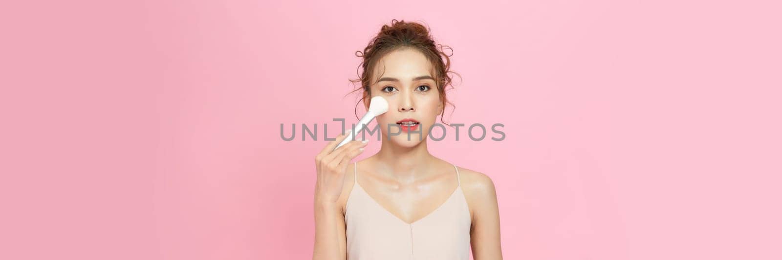 Closeup portrait of beautiful happy young girl with perfect skin is holding makeup brush in hand. by makidotvn