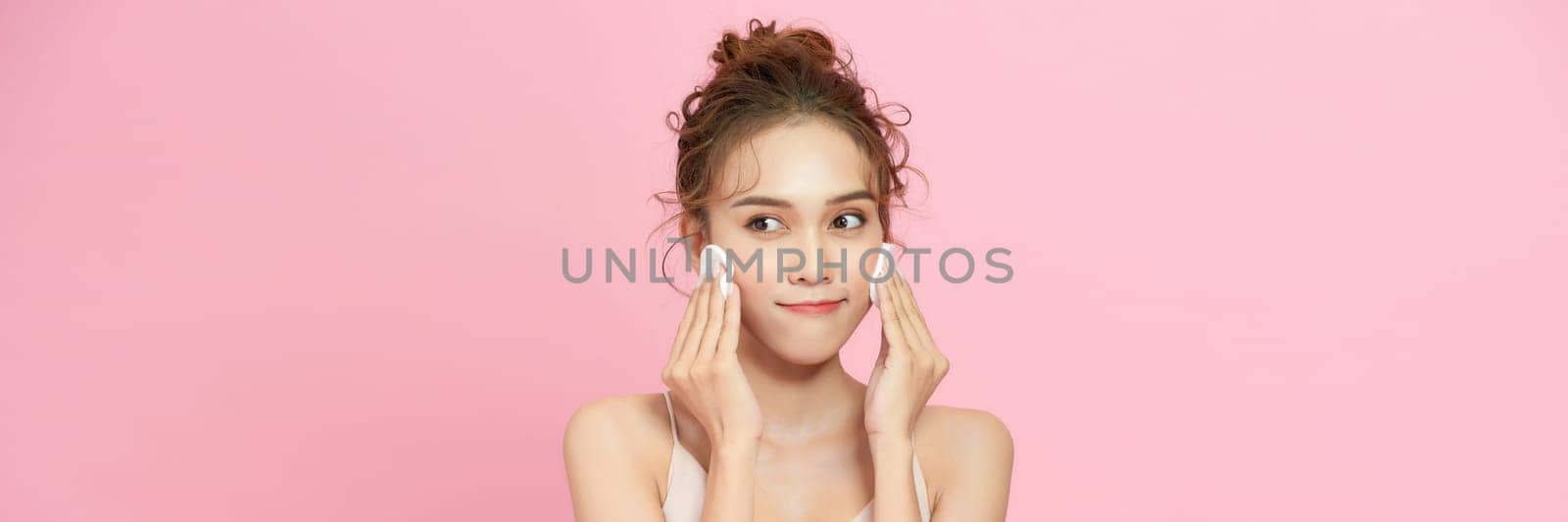 Young attractive lady using face toner and cotton pad