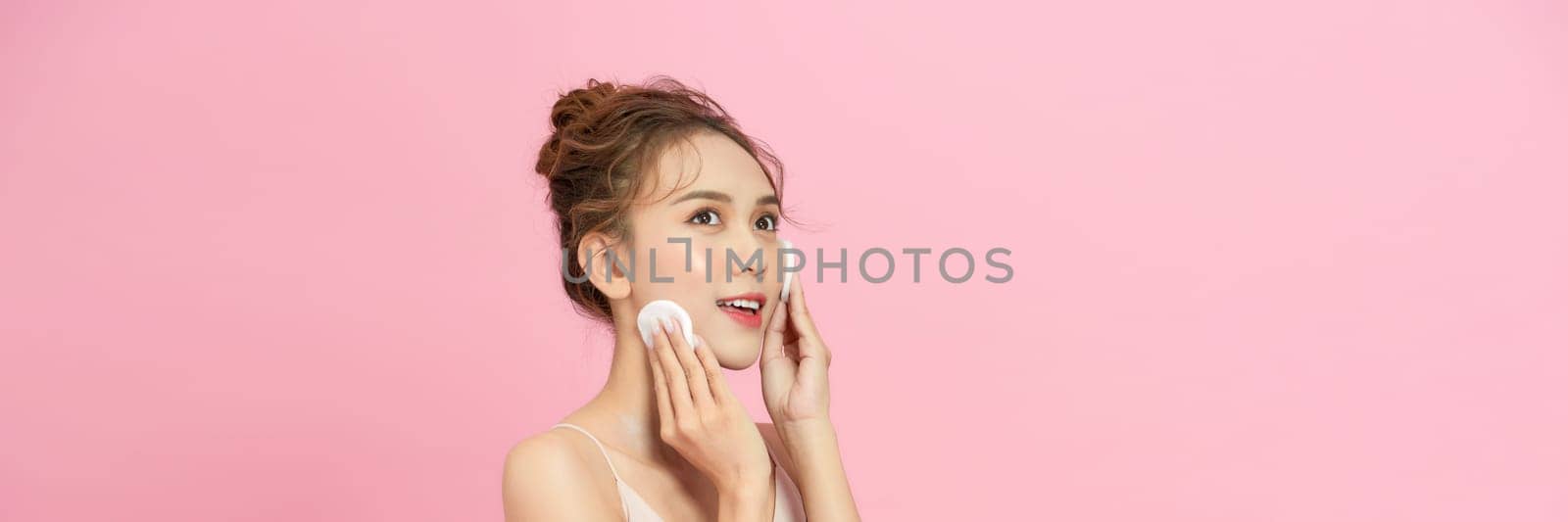 Attractive Asian young woman smile and using cotton with toner cleaning make up so fresh and clean