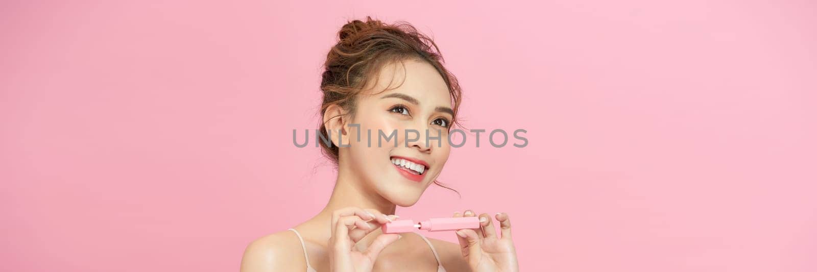 Young woman applies lipstick on lips