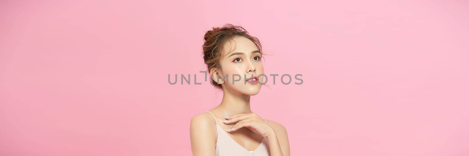 Beautiful young asian woman with clean fresh skin on pink background, 