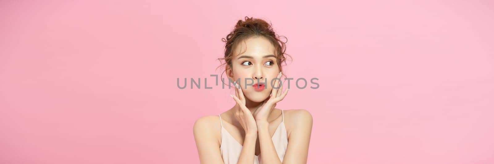 Young happy asian teen woman thinking something isolated on pink background. by makidotvn