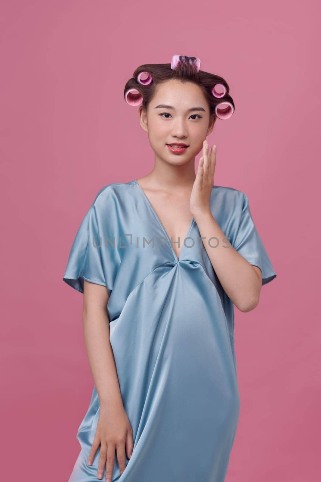 Beautiful young woman in hair rollers on pink background by makidotvn