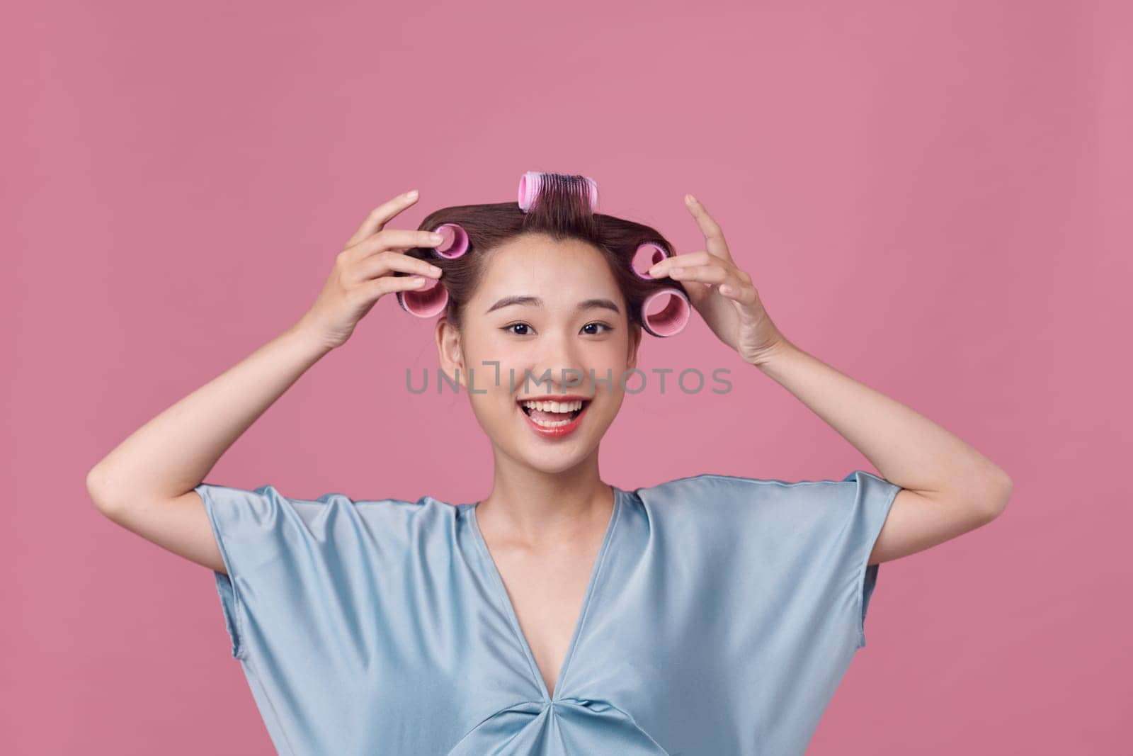 Beautiful woman with hair-curlers doing funny faces by makidotvn