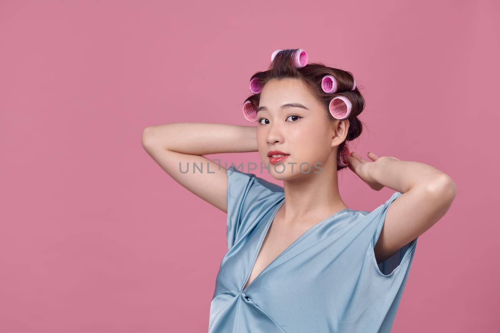 Seductive young lady in hair rollers posing and looking away on white background