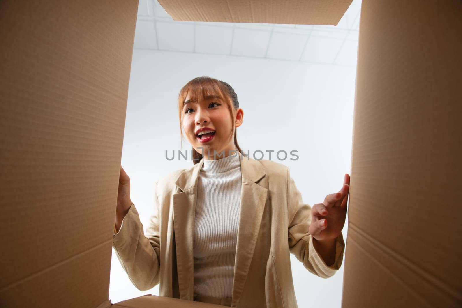 Young beautiful girl, opens and peeks into cardboard box. Bottom view 