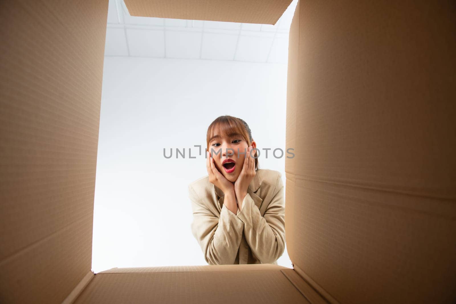 Happy laughing young woman putting arms into box, feeling excited receiving order from internet store by makidotvn