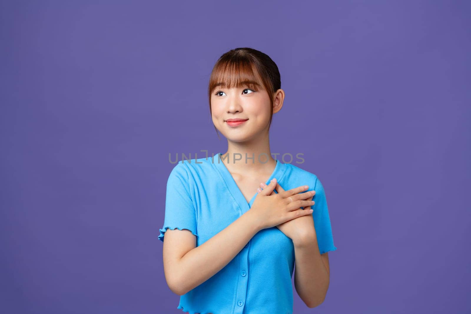 Happy pleased pretty young woman holding hands on chest feeling gratitude, standing isolated at white background by makidotvn