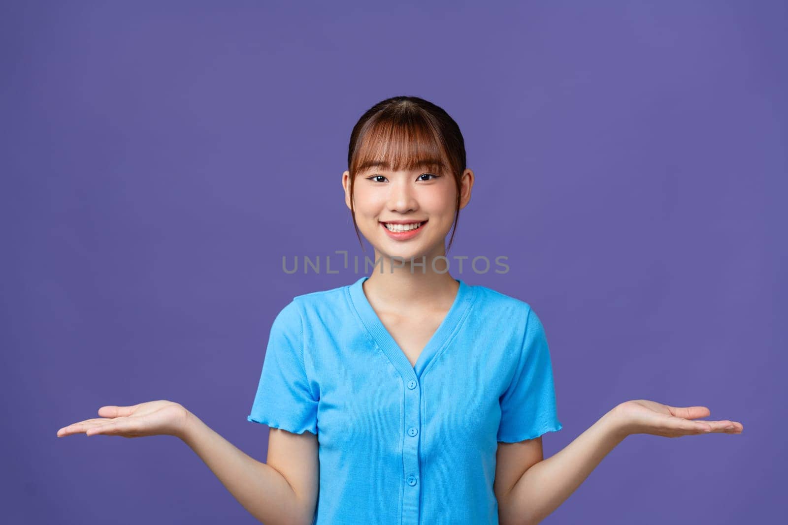 Asian beautiful young woman show both hands with open palms on upper side with smile face.