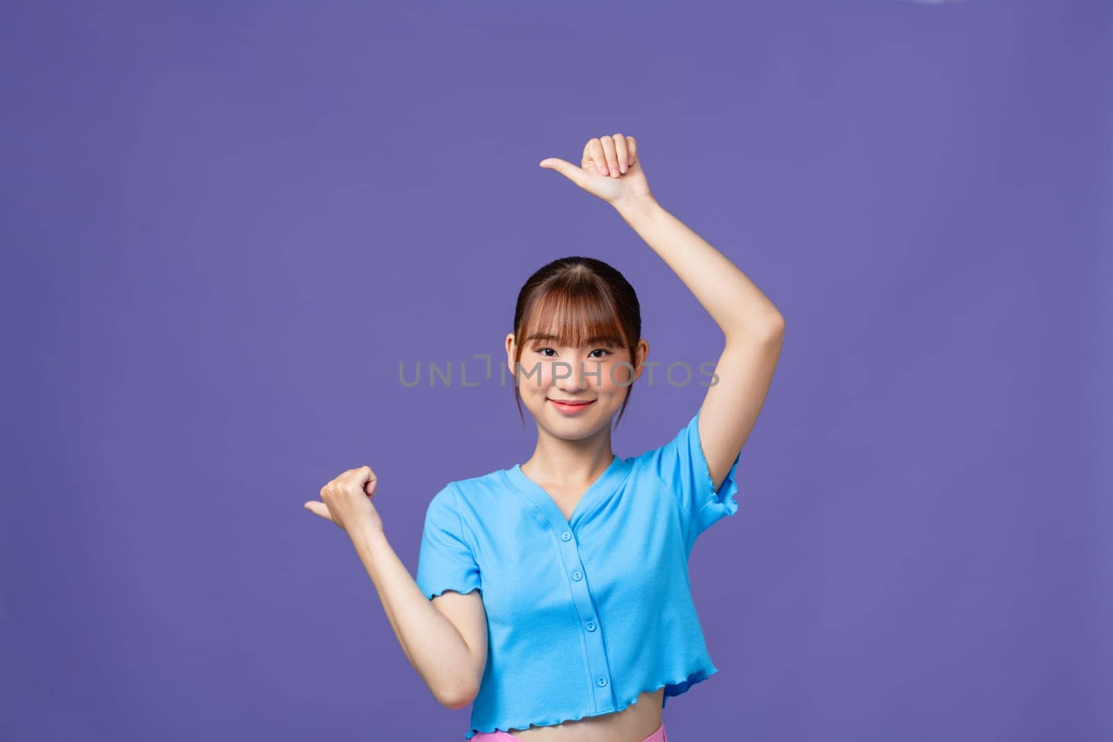 attractive cheerful girl demonstrating copy space ad new isolated over purple background by makidotvn