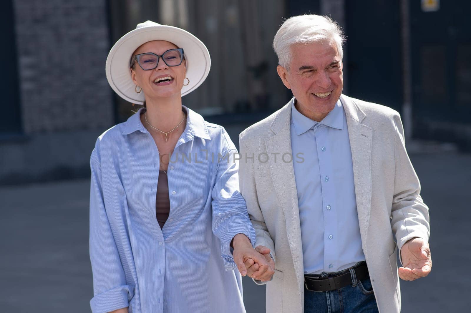 Stylish elderly laughing couple on a walk. Romantic relationships of mature people. by mrwed54