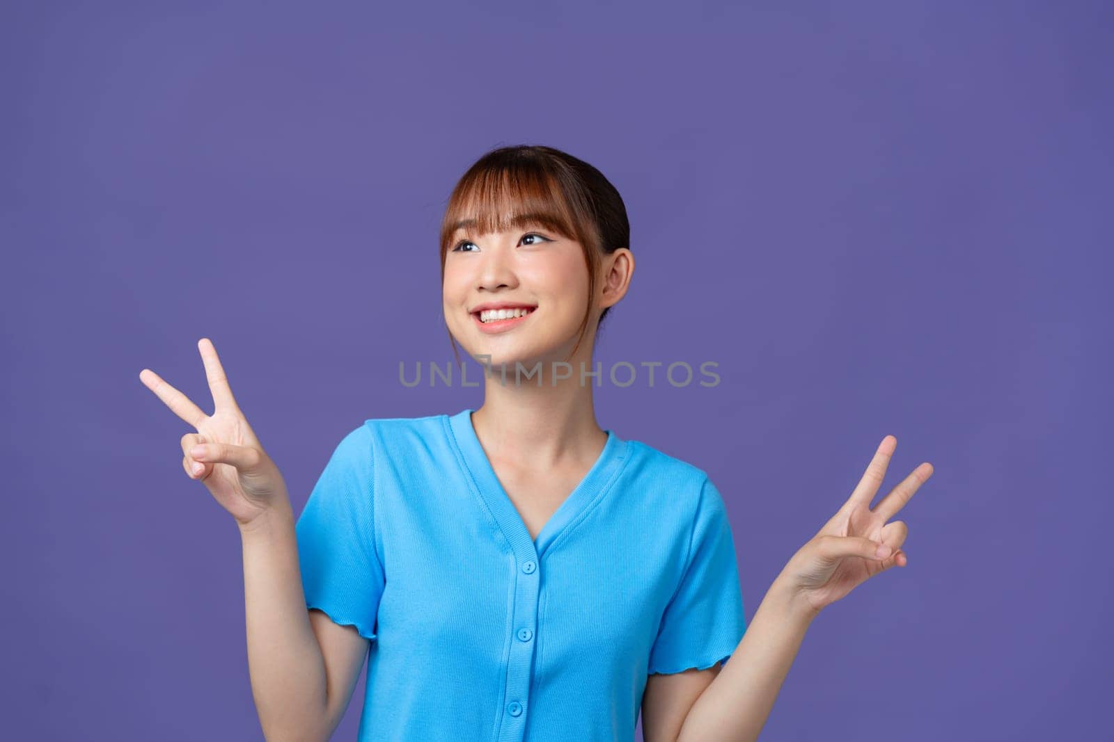 Portrait of funky pretty young person beaming smile finger show v-sign isolated on purple background