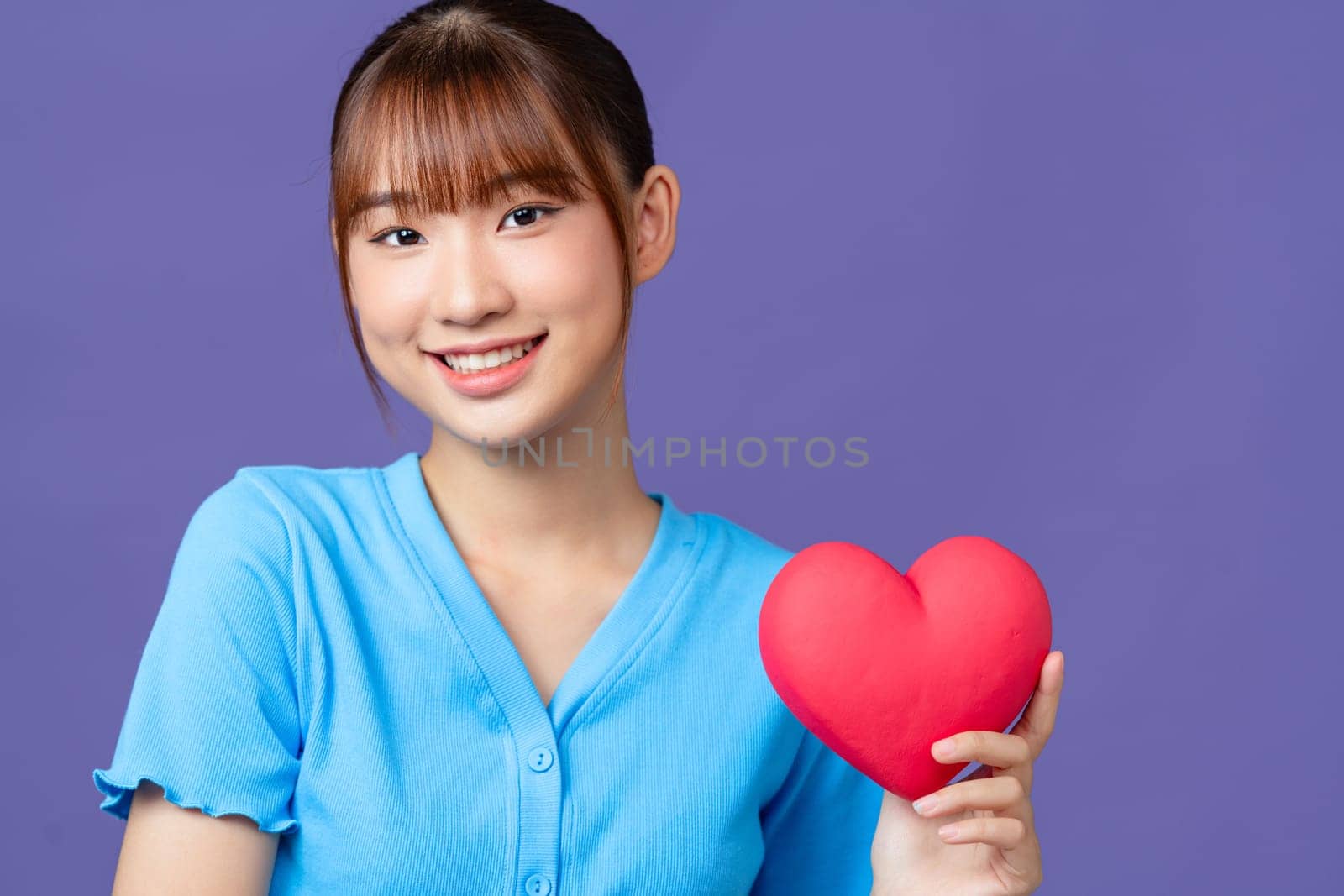 Attractive woman with heart, isolated on purple background