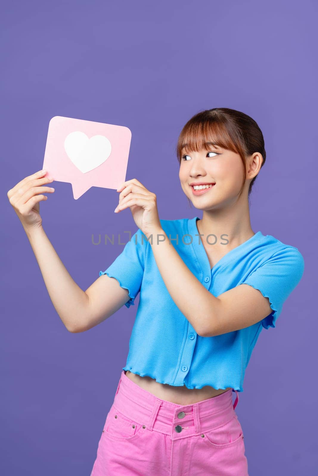 Photo of funny young asian lady show like wear blue crop-top isolated on purple background by makidotvn