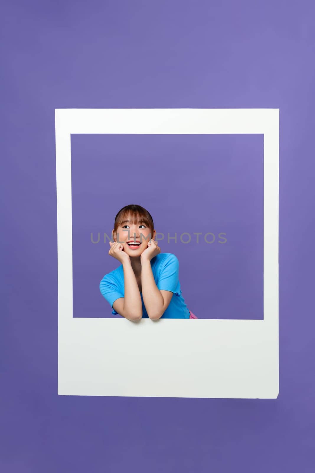 Cute young lady toothy smile hold white photo frame dressed trendy blue clothes by makidotvn