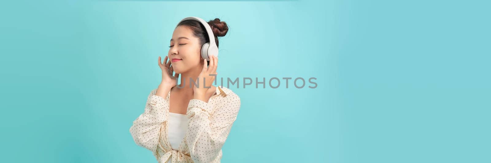 young student with big headphones among blue studio background by makidotvn