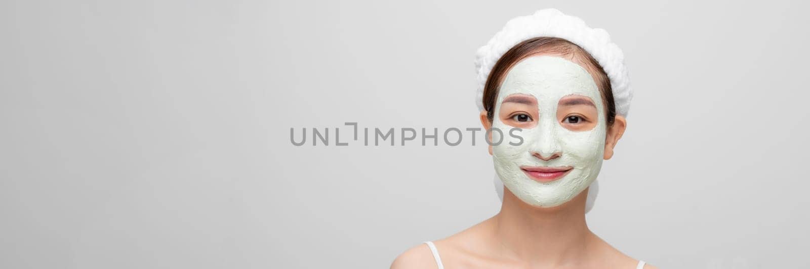 Skin care. Young woman with cosmetic clay mask on white banner by makidotvn