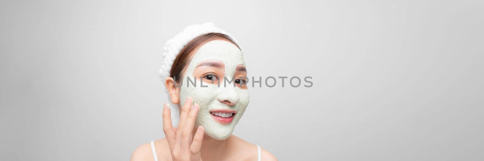 beautiful young woman doing cosmetic mask on her face - white background. Web banner by makidotvn