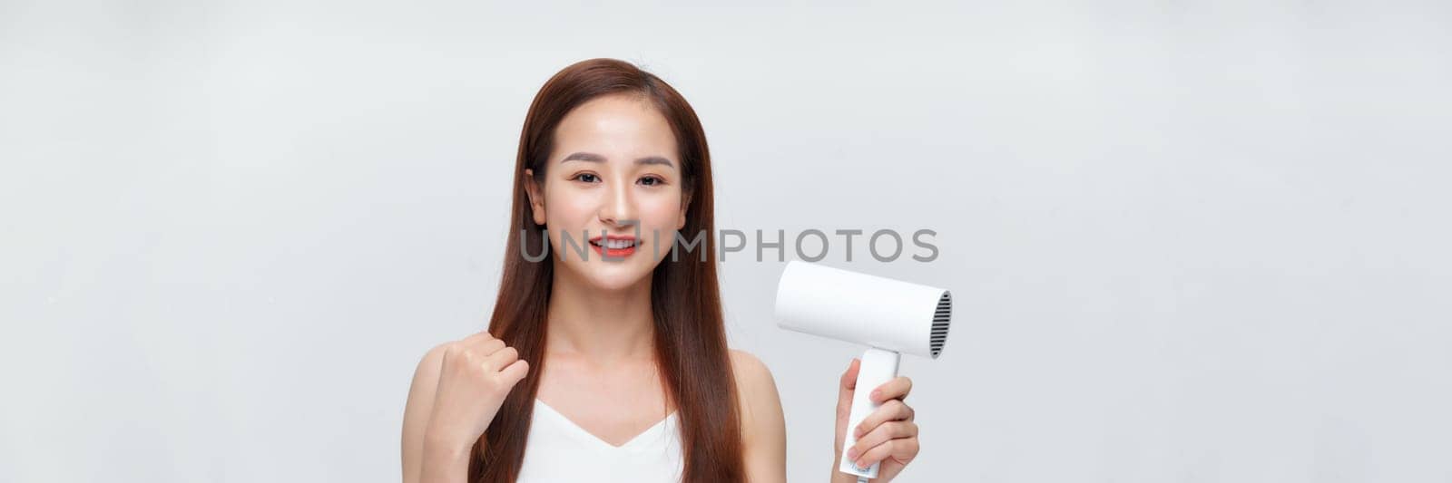 Woman dries her beautiful long hair with a hair dryer against a white background. Web banner by makidotvn