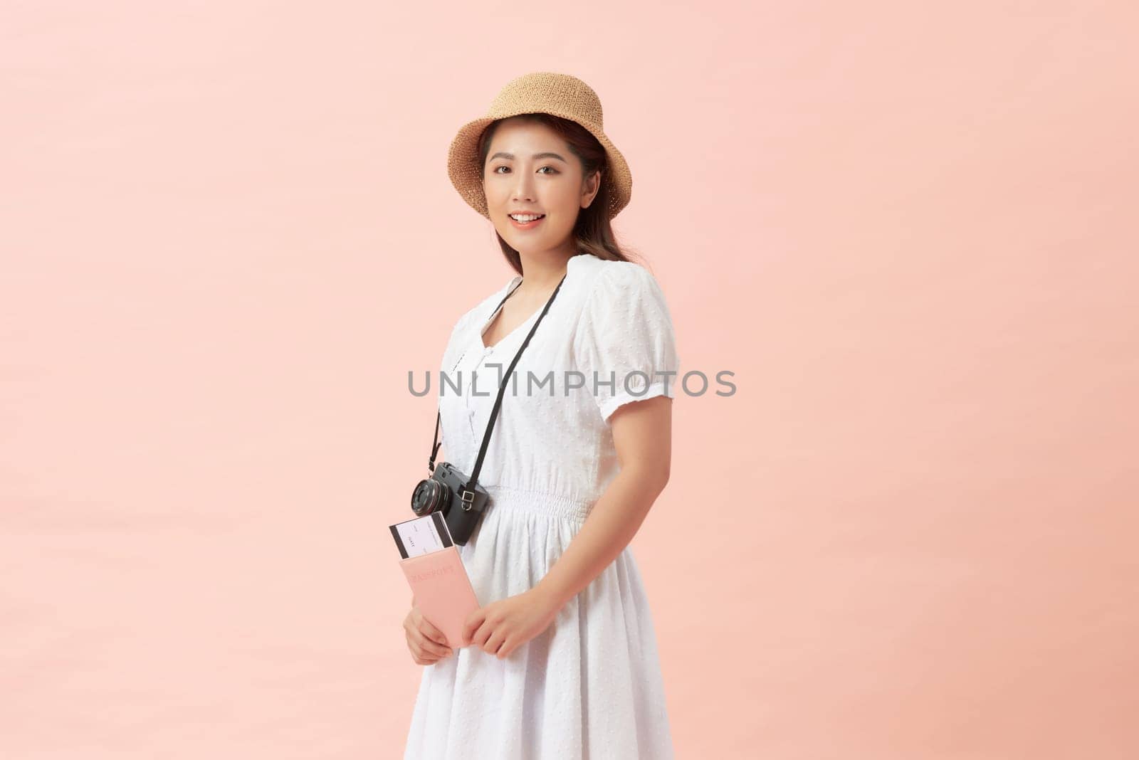 Happy tourist woman wearing hat with camera passport tickets look camera isolated on pink background
