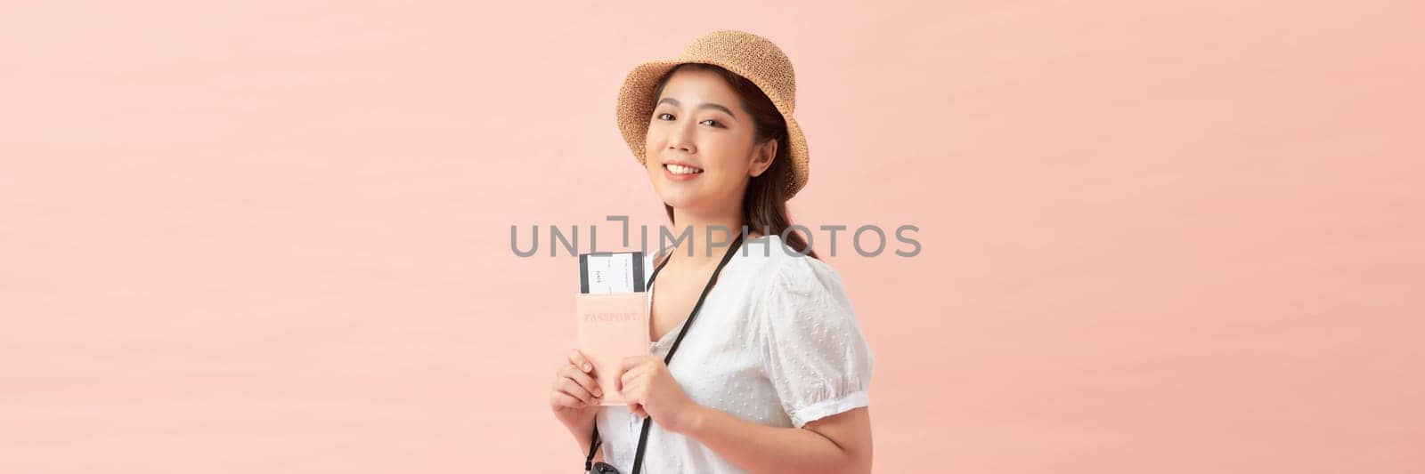 Young Asian woman with passport and ticket on pink background with space for text for banner