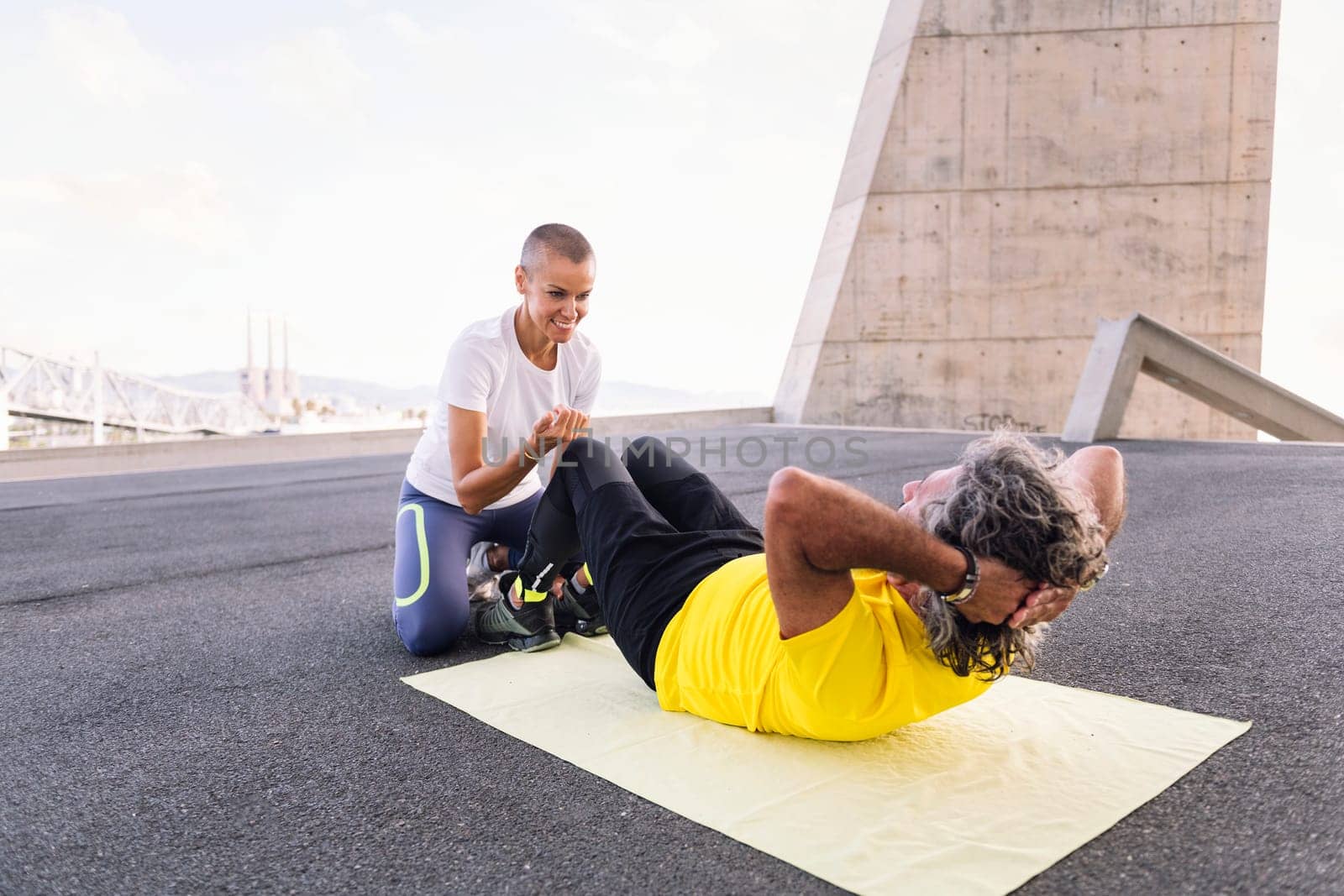 female personal trainer assisting a senior sports man with abs workout, concept of active and healthy lifestyle in middle age