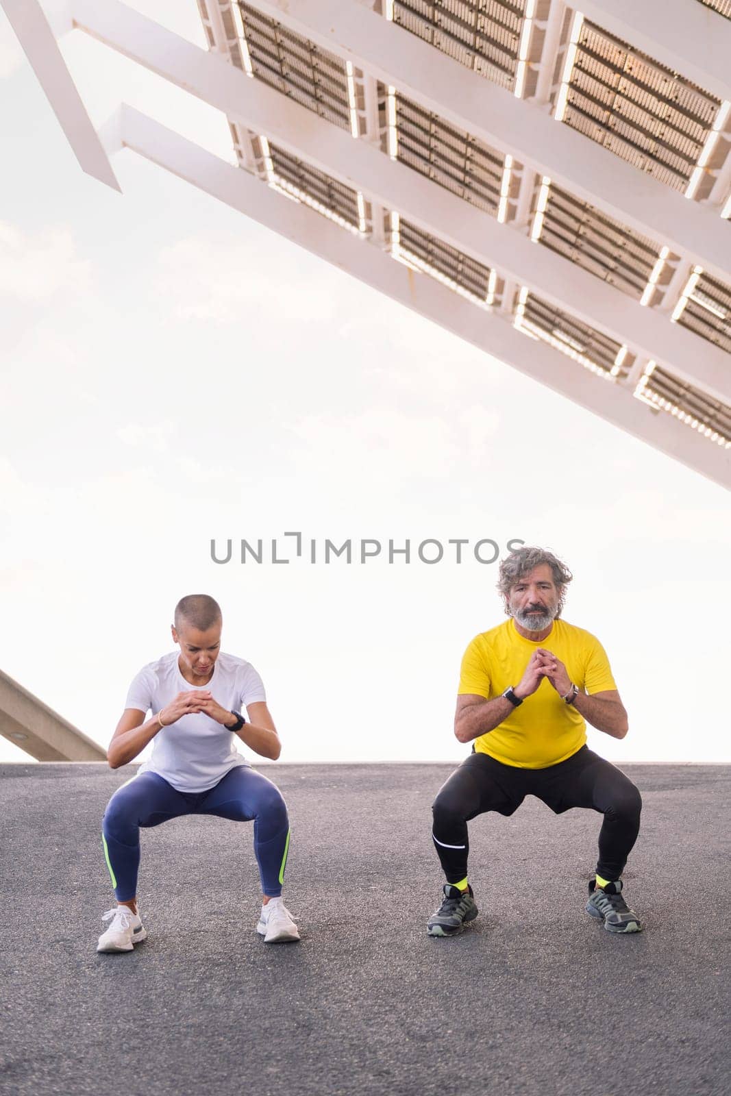 senior man doing a squat workout with his trainer by raulmelldo
