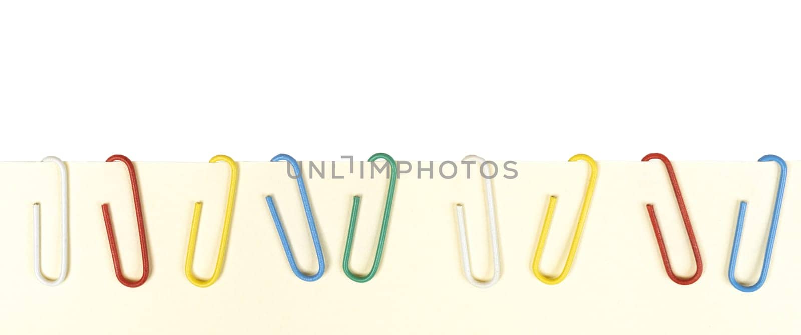 a row of colored paper clips on a blank sheet of paper