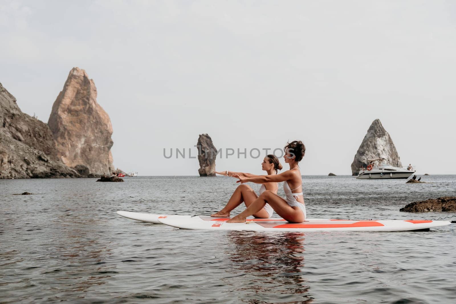 Woman sup yoga. Happy sporty woman practising yoga pilates on paddle sup surfboard. Female stretching doing workout on sea water. Modern individual female hipster outdoor summer sport activity. by panophotograph