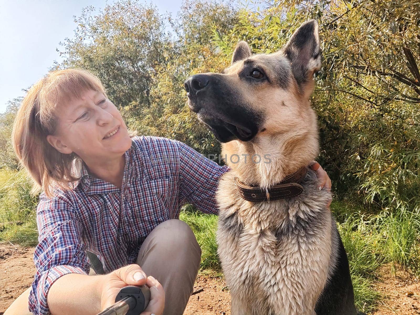 Adult girl with shepherd dog taking selfies in a forest. Middle aged woman and big shepherd dog on nature. Friendship, love, communication, fun, hugs by keleny