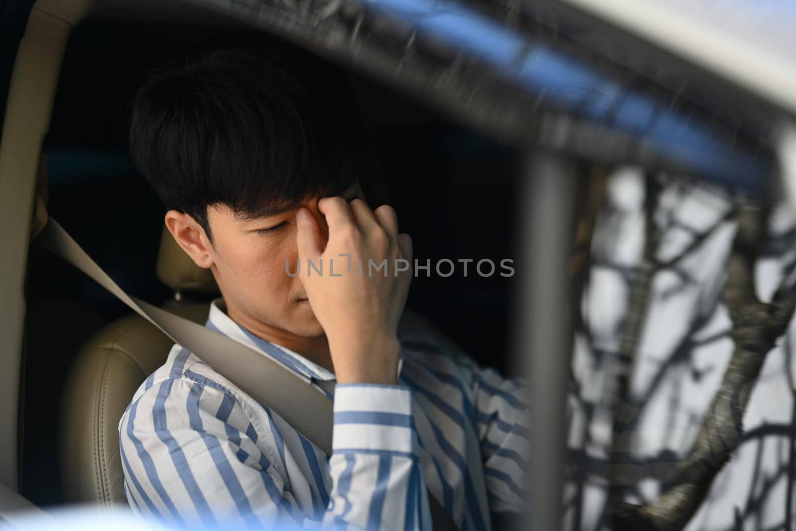 Stressed asian man rubbing nose sitting inside car driving. Transportation and vehicle concept concept