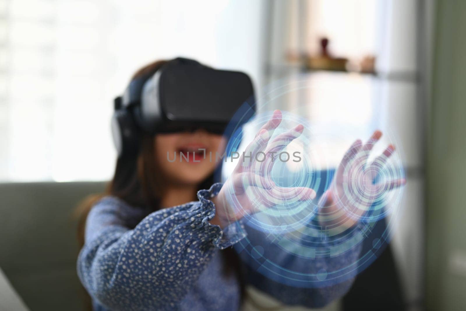 Excited little girl in VR headset touching virtual screen. Concept of futuristic technology