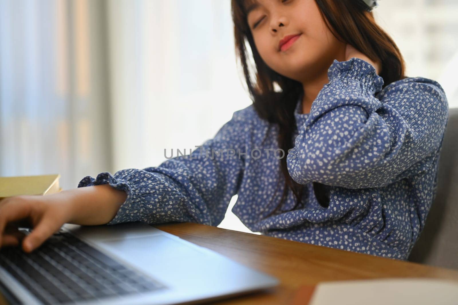 Exhausted schooler girl suffering from doing homework or studying online on laptop at home