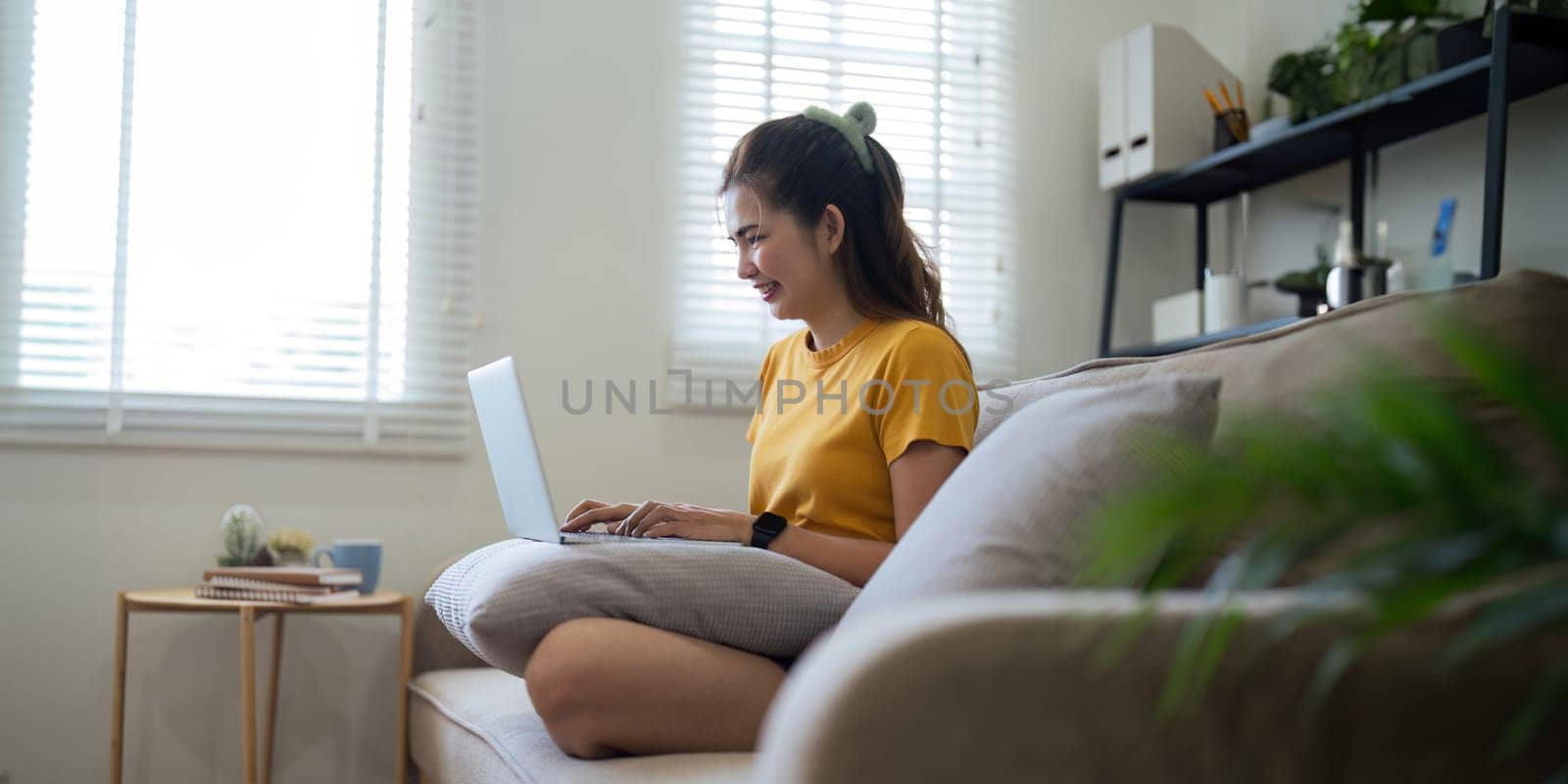 Young woman Asian using laptop pc computer on couch relax surfing the internet at home. lifestyle relaxation concept.